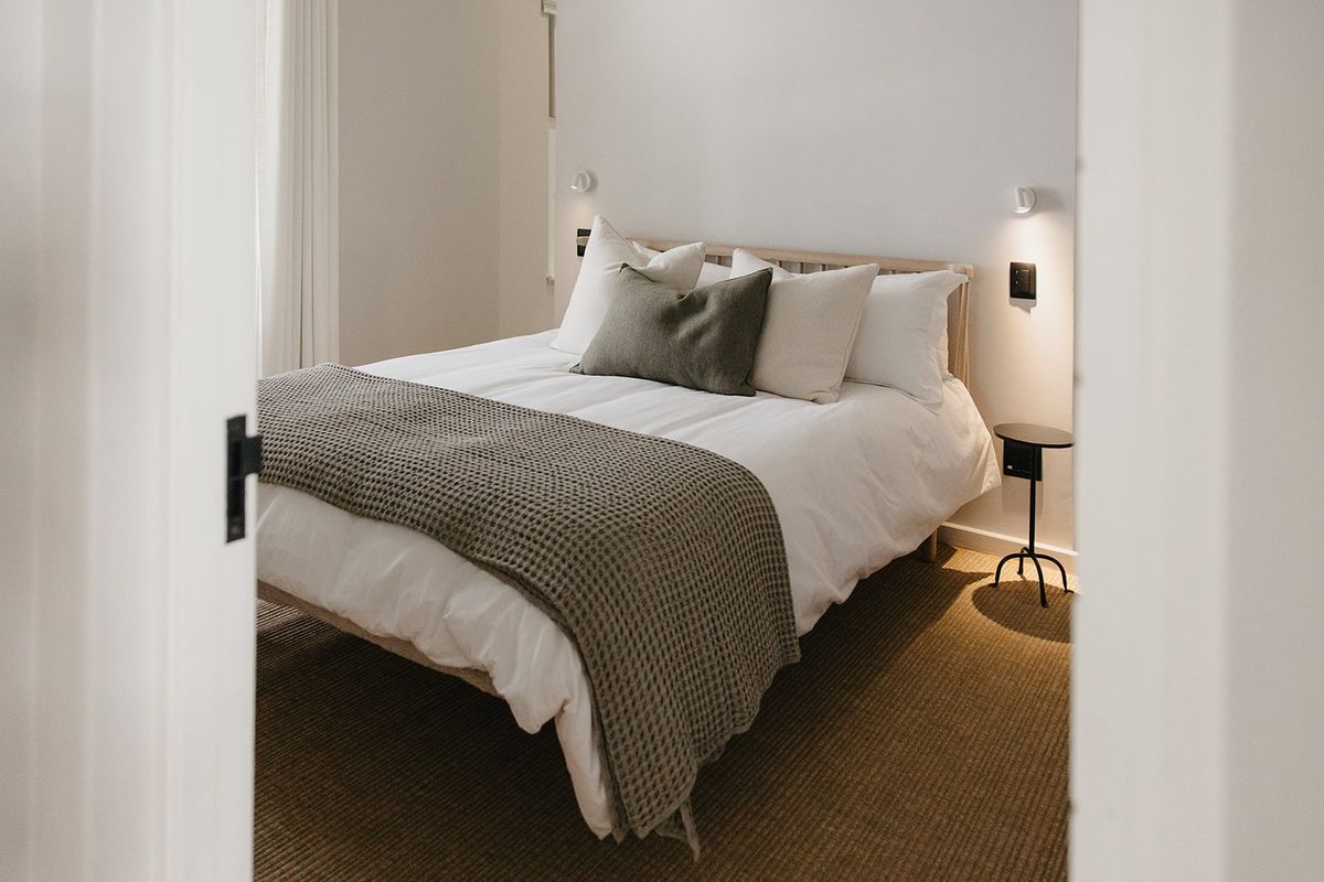 A well-maintained bedroom featuring neutral tones, recessed wall lighting, and integrated electrical fixtures, viewed through a doorway.