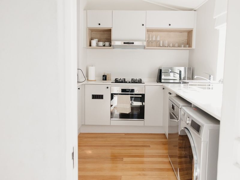 A modern, well-maintained kitchen featuring white cabinetry, integrated appliances, gas cooktop, and warm hardwood flooring.