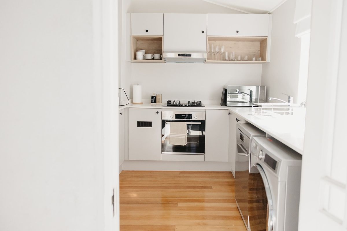 A modern, well-maintained kitchen featuring white cabinetry, integrated appliances, gas cooktop, and warm hardwood flooring.