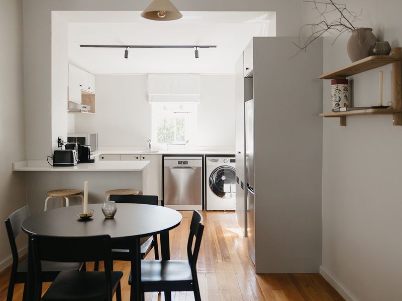 A bright open-plan kitchen and dining area featuring hardwood flooring, modern cabinetry, integrated appliances, and clean, minimalist finishes.