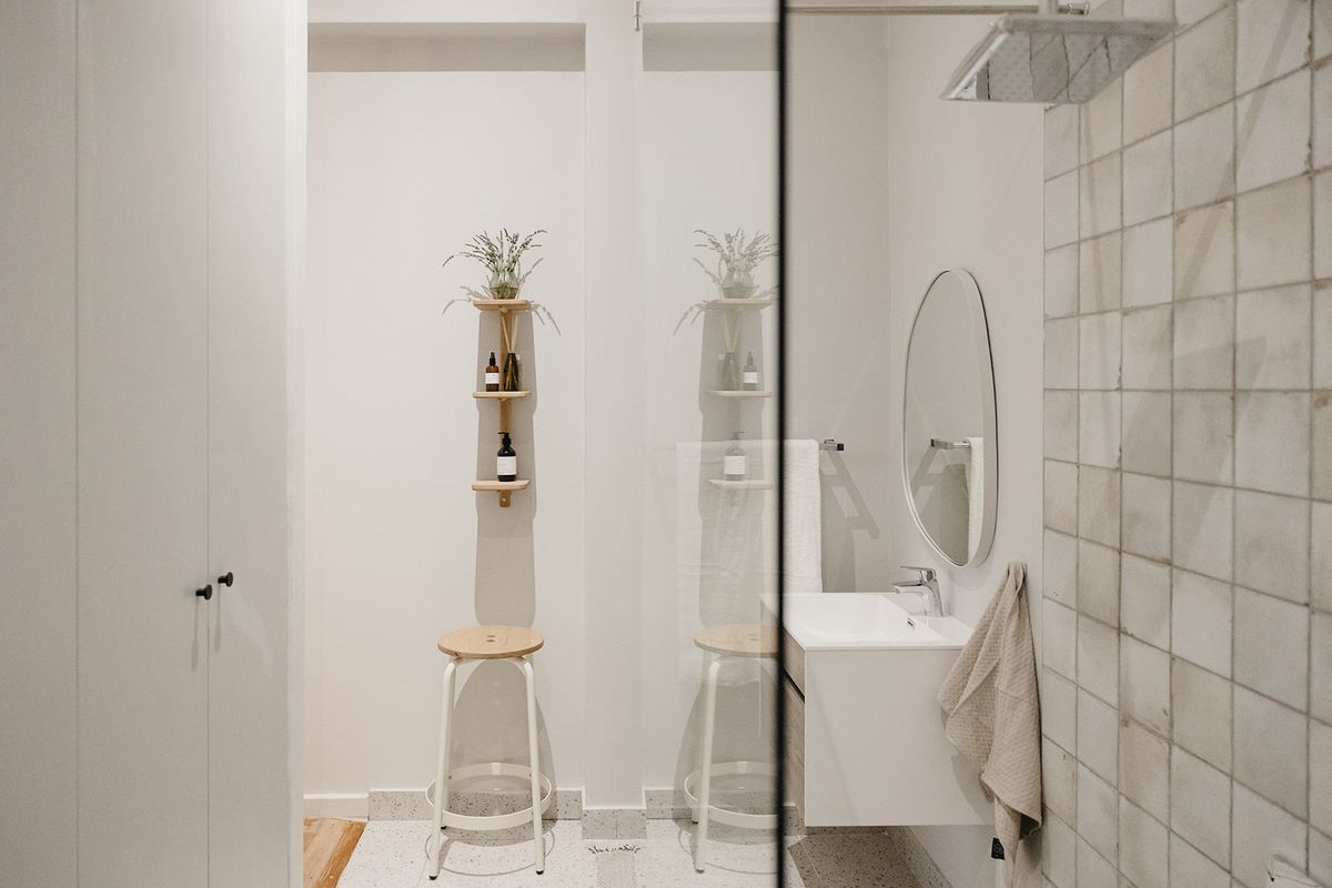 Modern bathroom featuring a wall-mounted vanity, basin, and a tiled shower area with a rainfall shower head and terrazzo flooring.