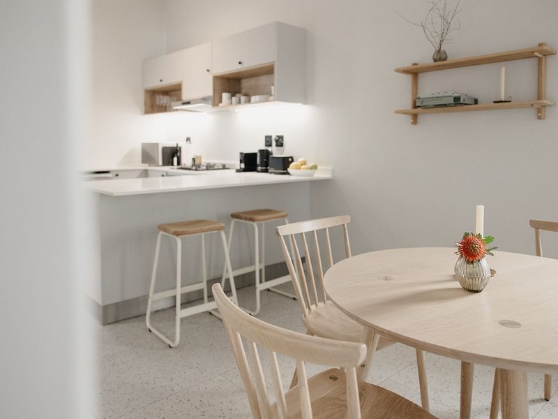 Modern open-plan kitchen and dining area featuring sleek cabinetry, stone countertops, under-cabinet lighting, and contemporary terrazzo flooring.