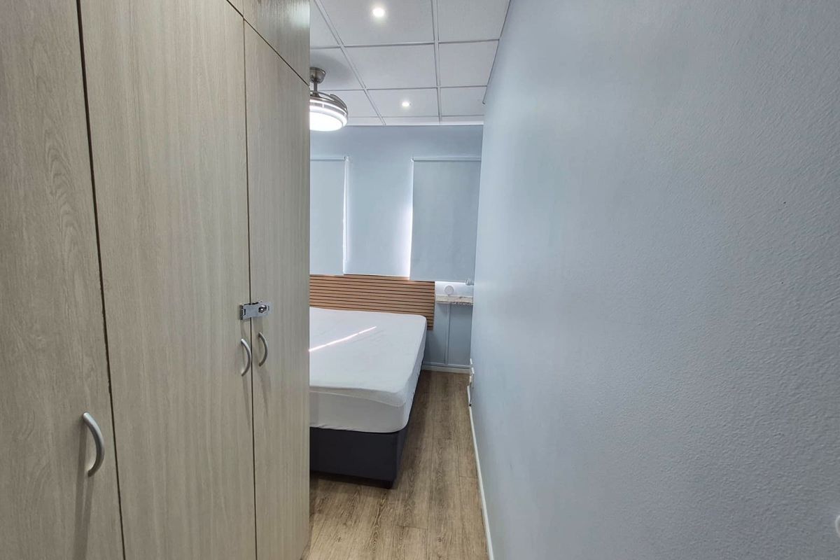 A bedroom featuring laminate flooring, built-in wardrobes, a drop ceiling with recessed lighting, and a ceiling fan.