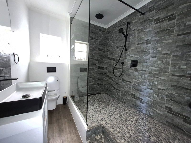 Modern bathroom featuring a spacious walk-in shower with stone tiling, a sleek wall-hung toilet, and a contemporary basin.