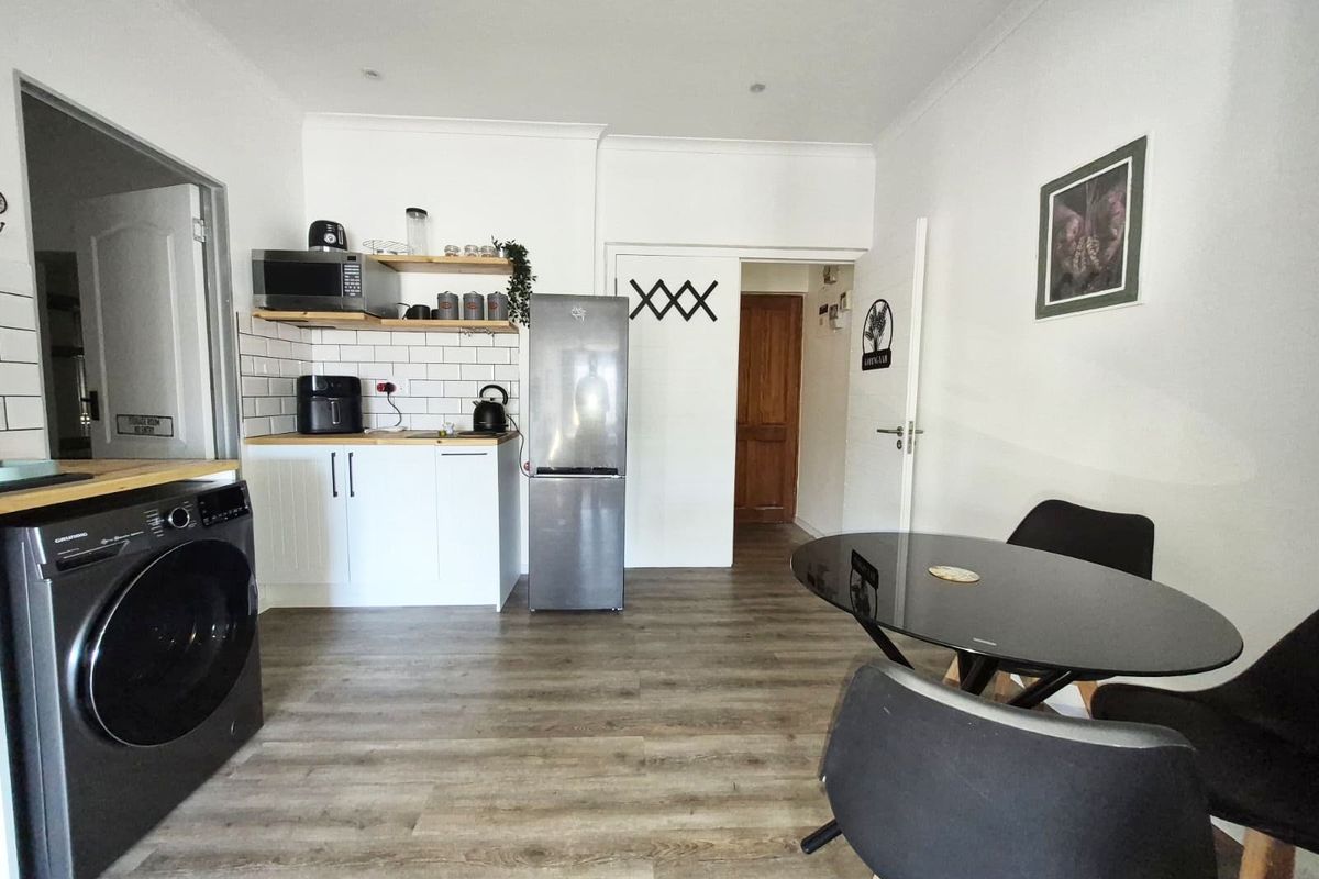 Open plan kitchen and living area featuring modern white cabinetry, subway tile backsplash, wood-look laminate flooring, and recessed lighting.