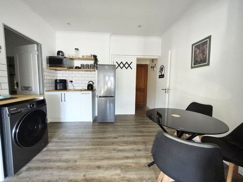 Open plan kitchen and living area featuring modern white cabinetry, subway tile backsplash, wood-look laminate flooring, and recessed lighting.