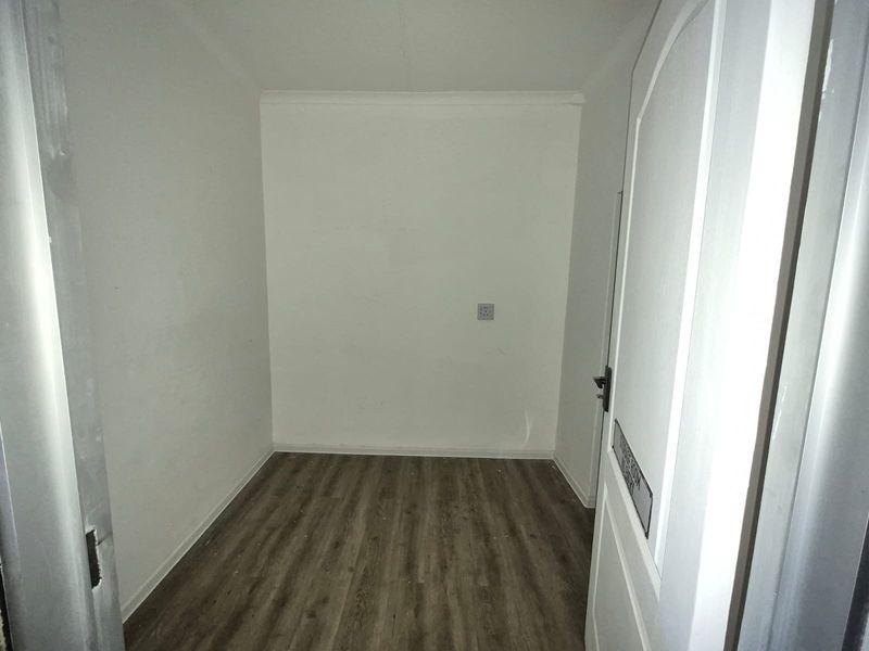 A clean, empty utility or storage room featuring modern laminate flooring and a neutral finish, suitable for various storage or functional uses.