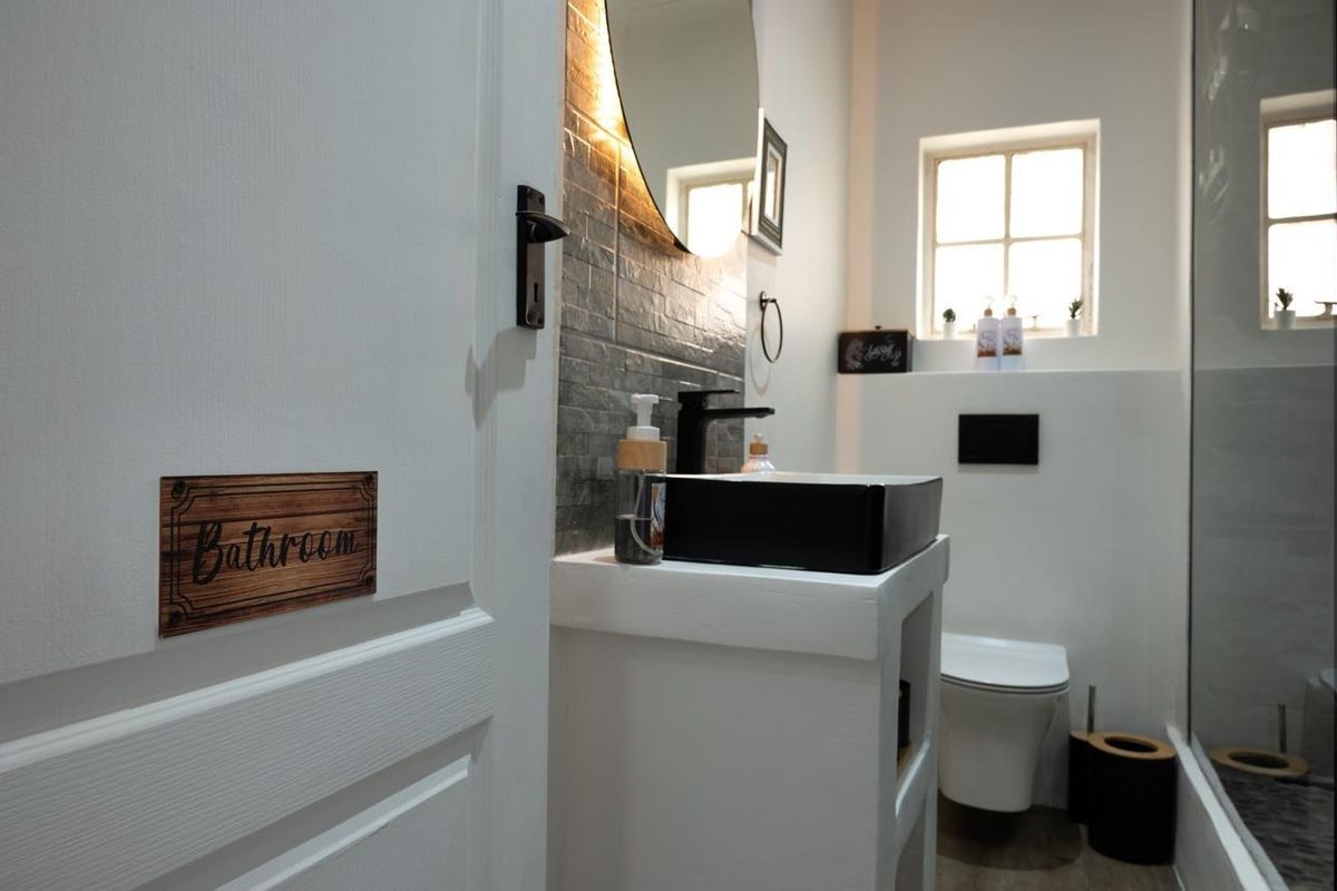 Modern bathroom featuring a vessel sink, wall-mounted toilet, and a glass-enclosed shower with contemporary finishes and tiled backsplash.