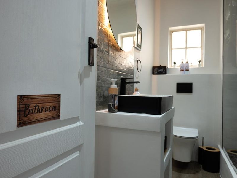 Modern bathroom featuring a vessel sink, wall-mounted toilet, and a glass-enclosed shower with contemporary finishes and tiled backsplash.