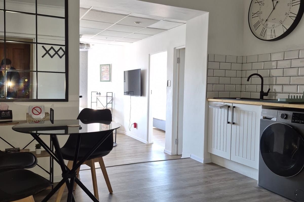 Open plan living area featuring a modern kitchen corner with subway tile backsplash, wood-look laminate flooring, and integrated cabinetry.