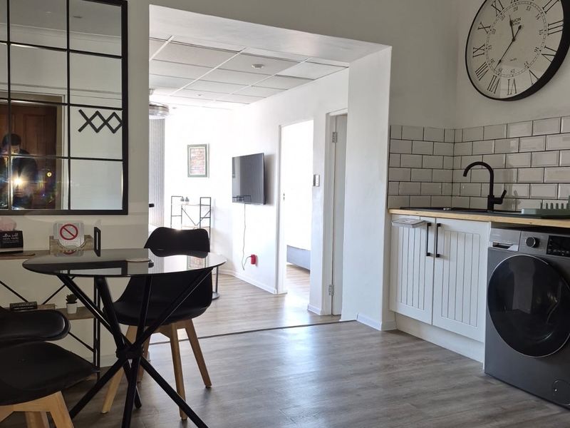 Open plan living area featuring a modern kitchen corner with subway tile backsplash, wood-look laminate flooring, and integrated cabinetry.