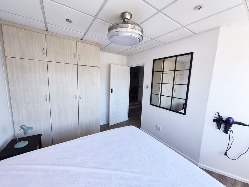 A well-maintained bedroom featuring built-in cupboards, a drop ceiling with integrated lighting, and durable laminate flooring.