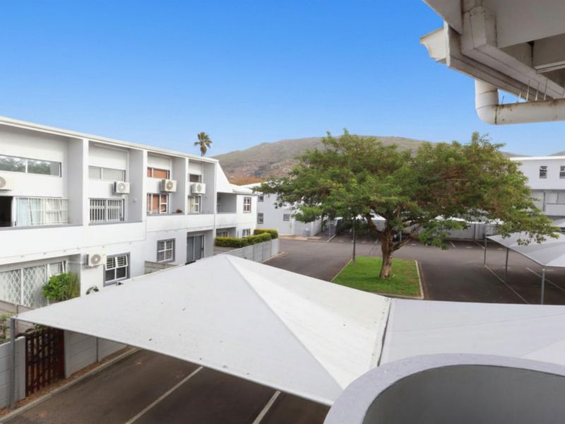 Elevated view overlooking the apartment complex parking area, featuring covered carports and well-maintained exterior building facades.