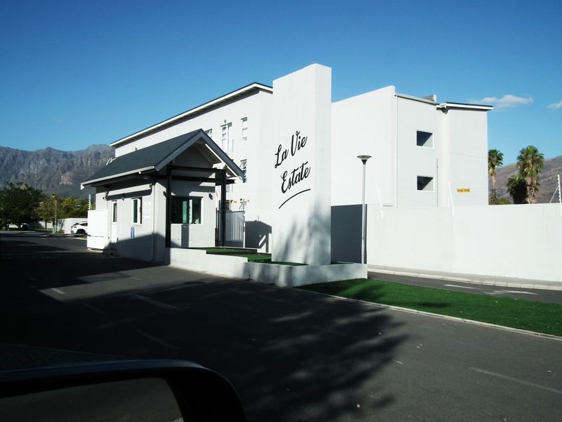 The entrance and security gatehouse of La Vie Estate, featuring modern perimeter walling, electric fencing, and well-maintained paved access.