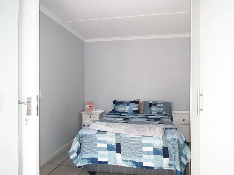 A compact bedroom featuring tiled flooring, neutral wall finishes, and built-in cupboard storage.