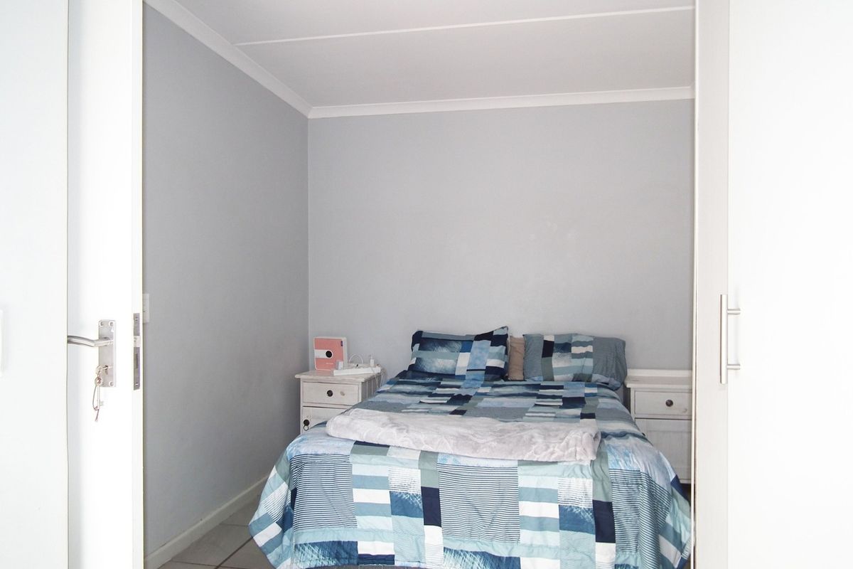 A compact bedroom featuring tiled flooring, neutral wall finishes, and built-in cupboard storage.