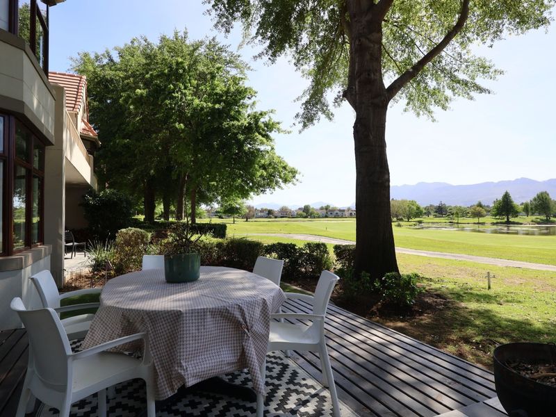 A spacious timber deck patio overlooking a scenic golf course and pond, offering a peaceful outdoor living space.