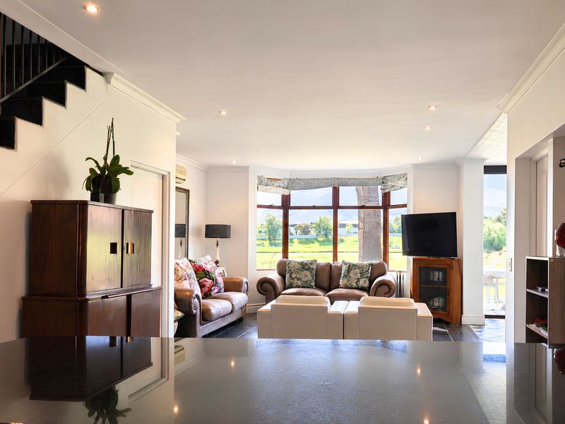Spacious open-plan living area featuring a staircase, large bay window with scenic views, recessed lighting, and dark tiled flooring.