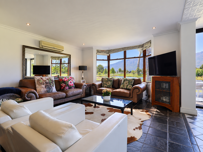 Spacious living room featuring large bay windows with scenic views, tiled flooring, and direct access to an outdoor patio area.