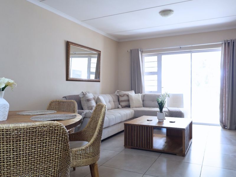A bright open-plan living and dining area featuring neutral tiled flooring and a large sliding glass door providing access to the outdoors.