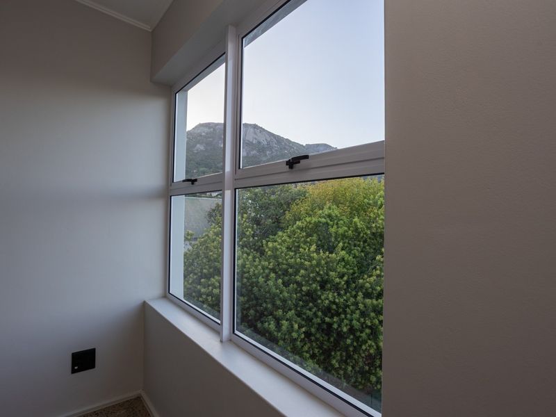 A bright interior space featuring a large window with a scenic mountain and garden view.