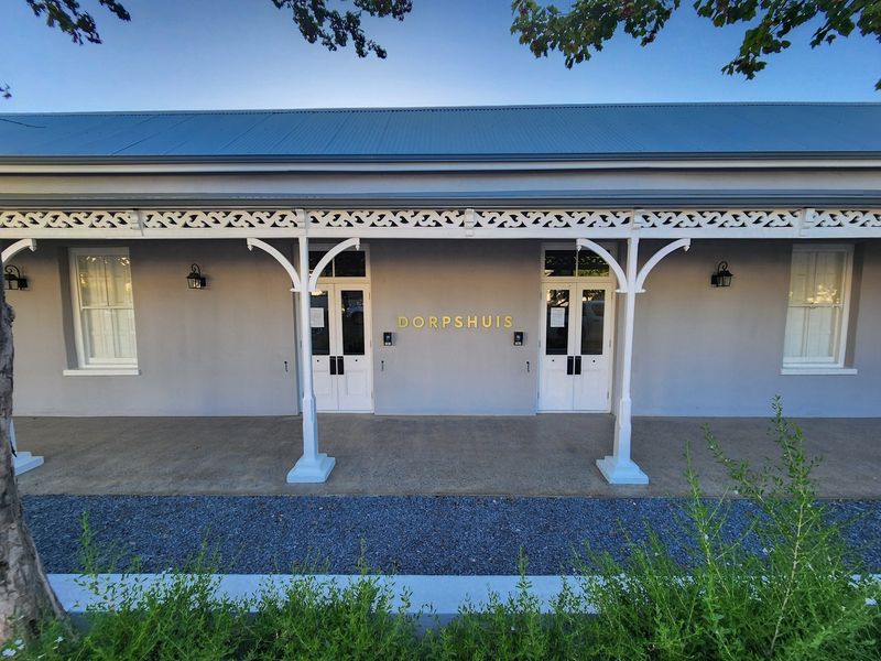 A well-maintained front facade featuring a covered veranda with decorative timber fretwork, double entry doors, and classic sash windows.