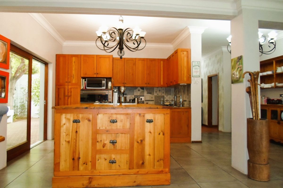 A spacious kitchen featuring natural wood cabinetry, a central island, tiled flooring, and direct access to an outdoor patio area.