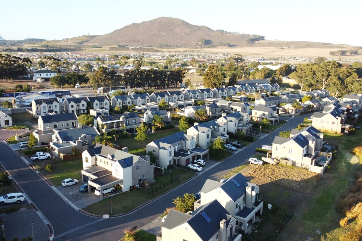 Aerial view of a residential estate featuring multiple homes, paved streets, and scenic mountain views in the background.