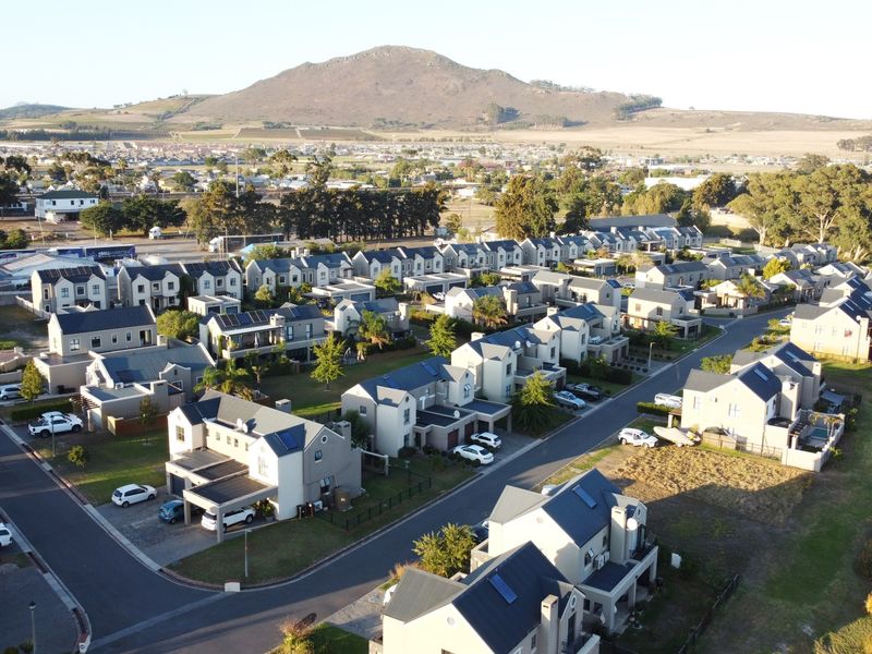 Aerial view of a residential estate featuring multiple homes, paved streets, and scenic mountain views in the background.
