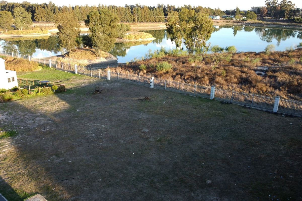Aerial view of a vacant residential plot featuring perimeter fencing and direct access to a scenic lake.