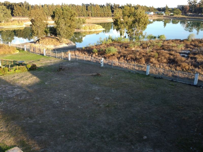Aerial view of a vacant residential plot featuring perimeter fencing and direct access to a scenic lake.