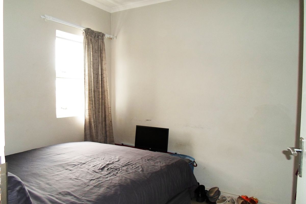 A simple bedroom featuring a window with curtain rod and neutral wall finishes.