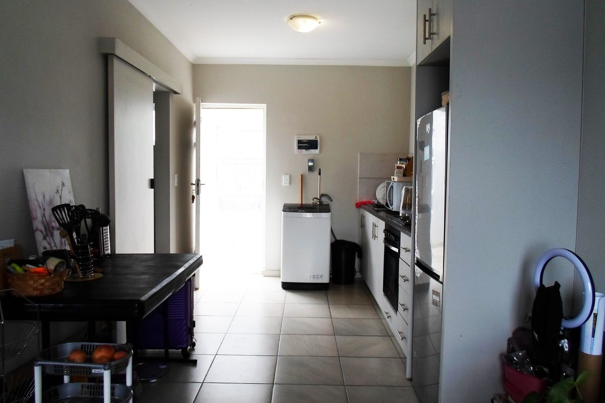 A functional kitchen featuring tiled flooring, built-in cabinetry, and integrated cooking appliances, with direct access to an exterior doorway.