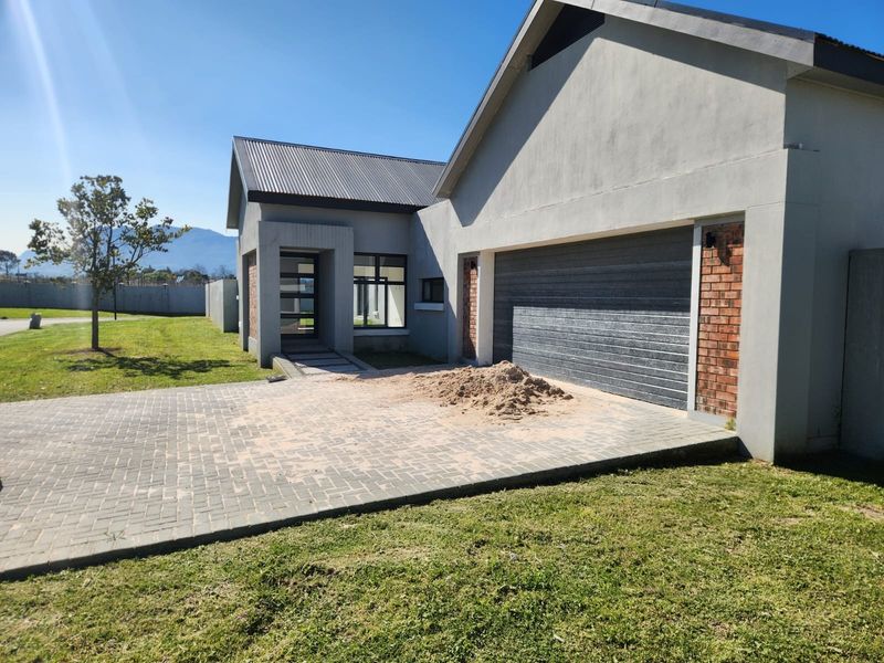 Front elevation of a modern house featuring a paved driveway, double garage, and covered entrance with brick detailing.