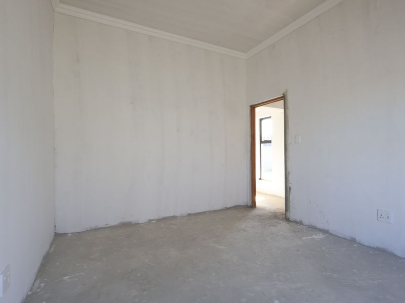 An unfinished bedroom space featuring raw plaster walls, concrete flooring, and coving, ready for final finishes and flooring installation.