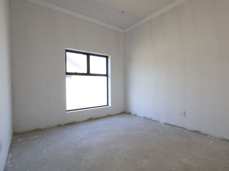 An empty, unfinished bedroom featuring plastered walls, a coved ceiling, and an aluminium-framed window, ready for final flooring and paint finishes.