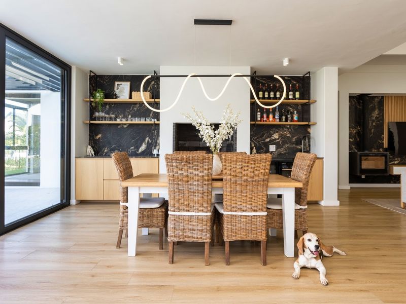 Modern dining area featuring built-in cabinetry with stone splashback, integrated fireplace, and large sliding glass doors opening to the exterior.