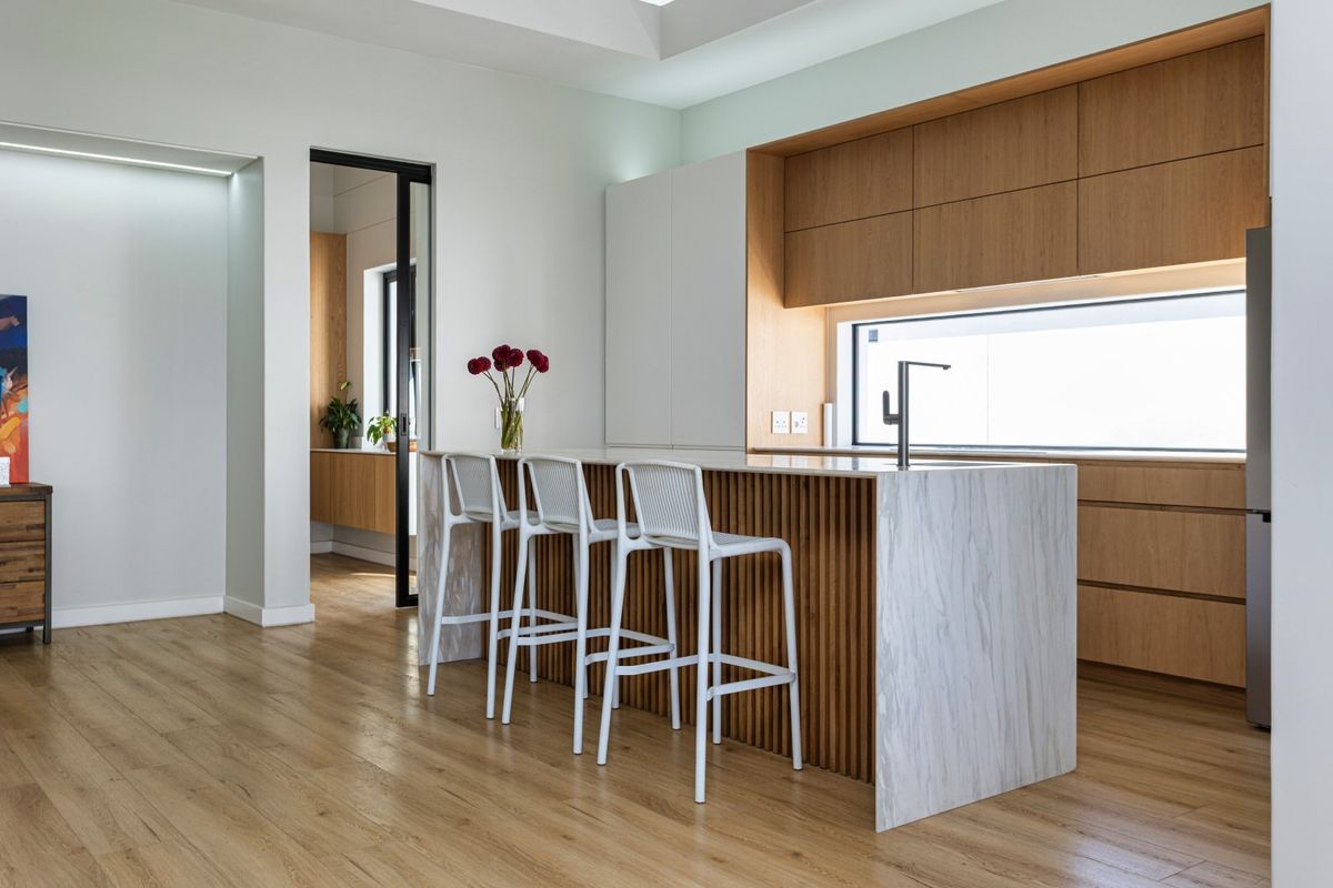 Modern kitchen featuring a marble-topped island with timber slat detailing, integrated cabinetry, and high-quality finishes throughout.