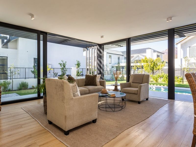 Bright and modern living area featuring expansive floor-to-ceiling sliding glass doors that provide seamless indoor-outdoor flow to the garden and pool area.