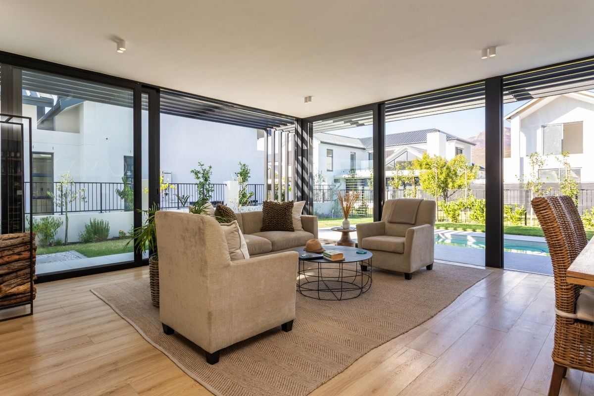 Bright and modern living area featuring expansive floor-to-ceiling sliding glass doors that provide seamless indoor-outdoor flow to the garden and pool area.
