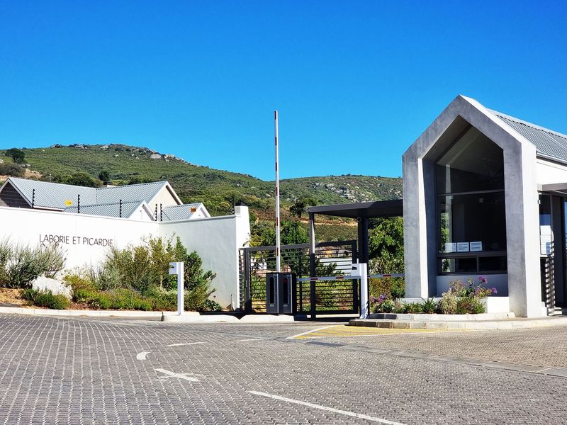 The secure entrance to Laborie et Picardie estate, featuring a paved driveway, boom gate access, and a modern guard house.