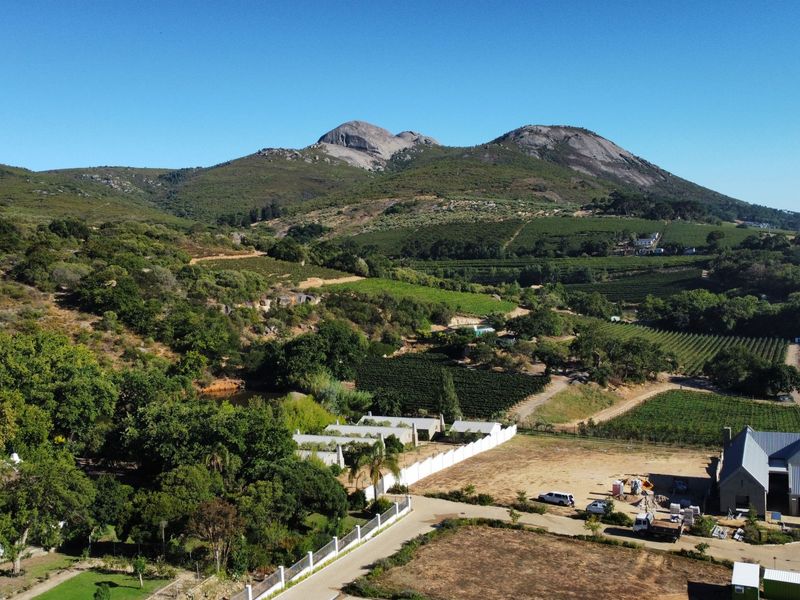 Aerial view of a residential property featuring expansive landscape, mountain backdrop, and existing building structures within a rural setting.
