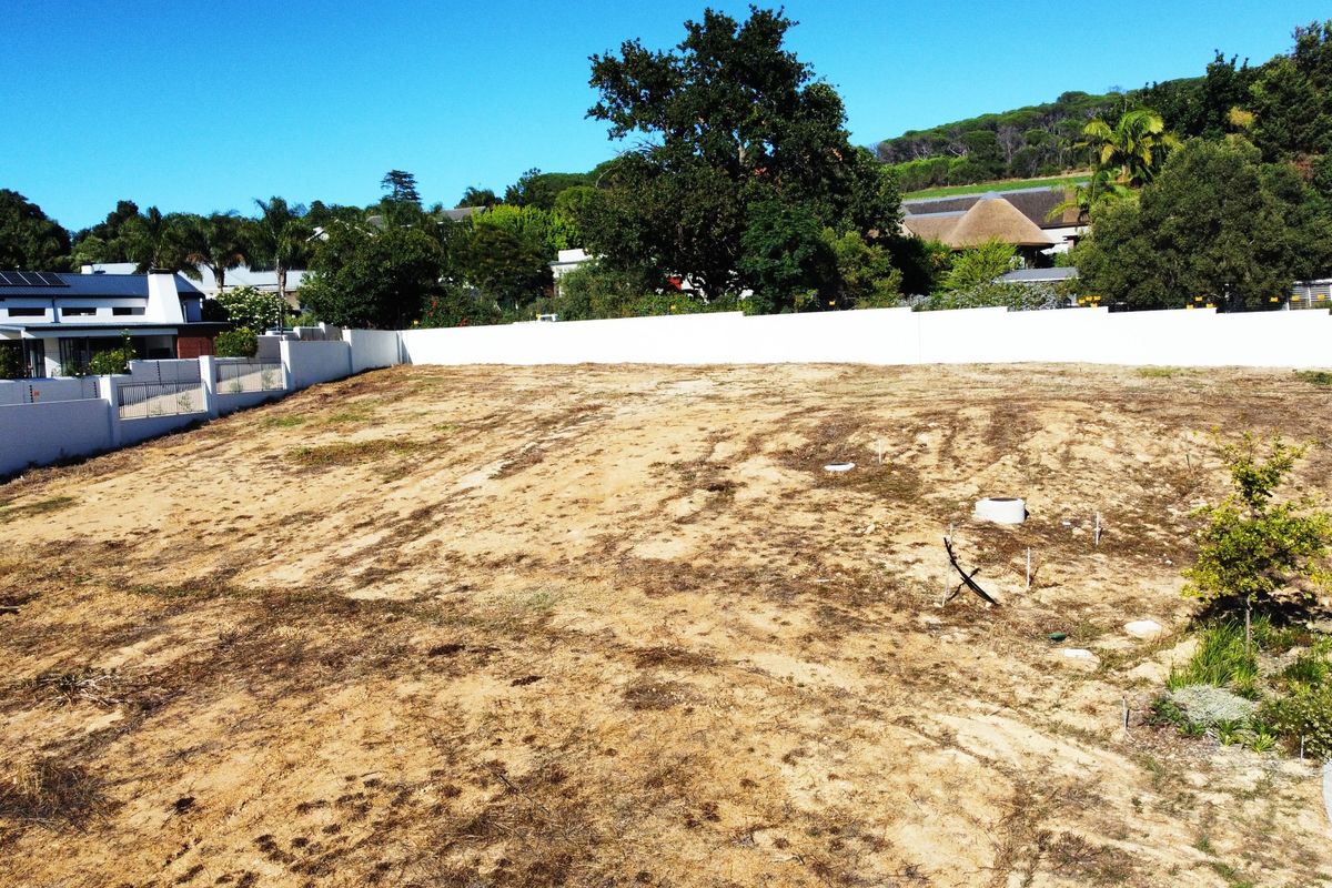 A vacant residential plot featuring a cleared surface, perimeter boundary walls, and established surrounding neighborhood vegetation.