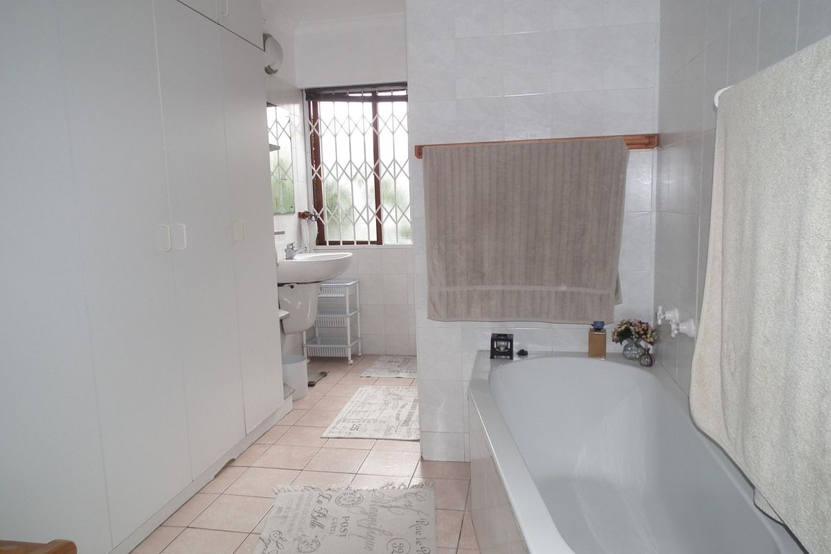 A functional bathroom featuring a bathtub, pedestal basin, and extensive built-in cabinetry with tiled flooring and wall finishes.