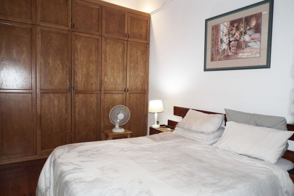 A bedroom featuring extensive built-in wooden cabinetry and hardwood flooring, offering ample storage space.