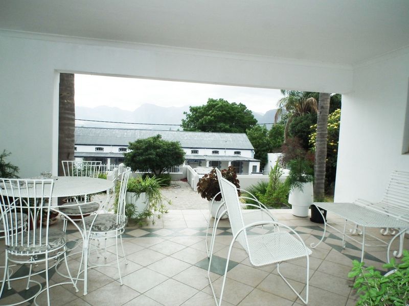 A covered patio area featuring tiled flooring and views of the surrounding garden and mountain landscape.