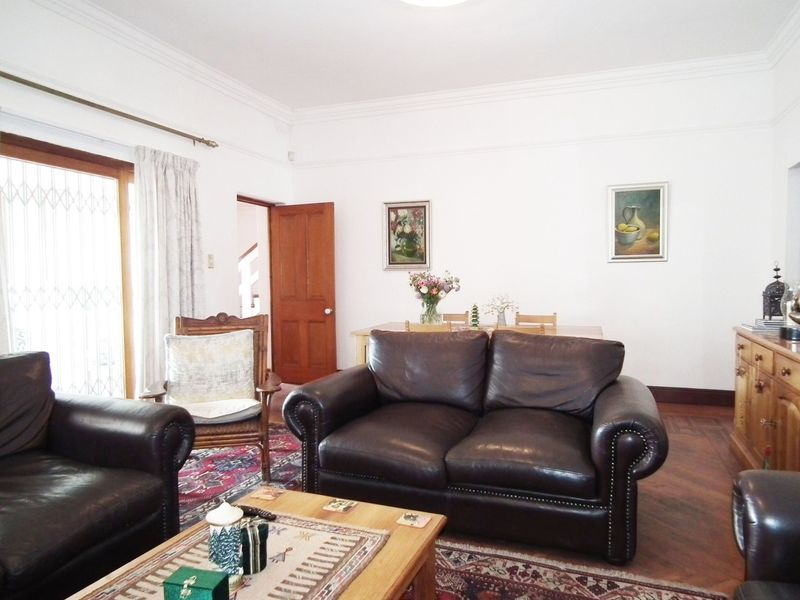 A spacious living room featuring classic parquet flooring, decorative cornicing, and a sliding glass door providing access to the exterior.
