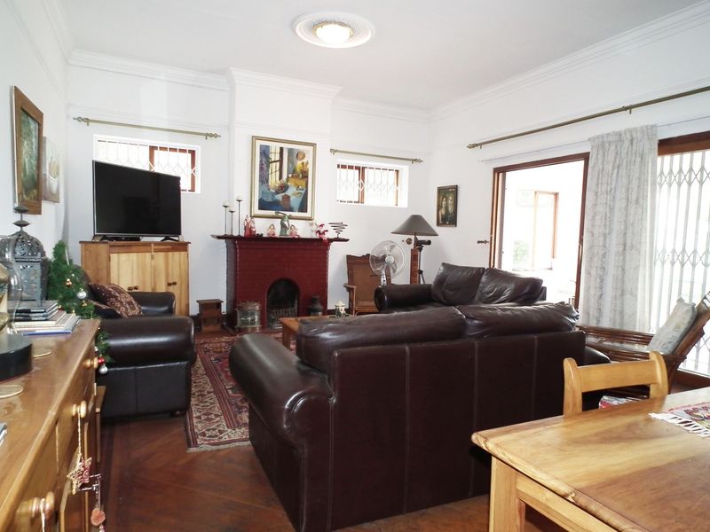 Spacious living room featuring a traditional fireplace, parquet flooring, and direct access to the outdoor area through sliding doors with security gates.