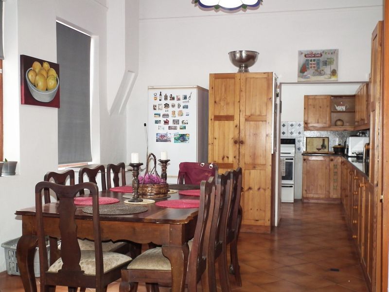 Open plan kitchen and dining area featuring terracotta floor tiles, wooden cabinetry, and a functional layout with integrated cooking appliances.