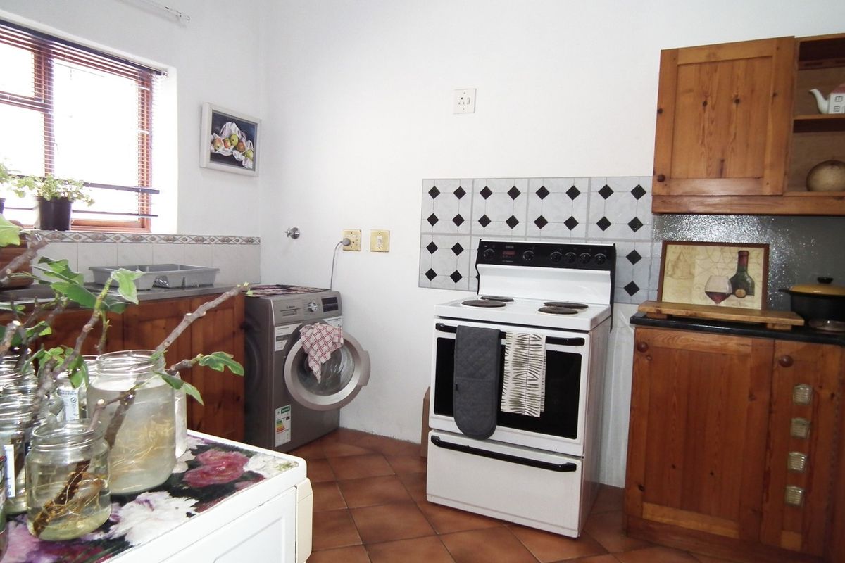 A functional kitchen featuring wooden cabinetry, tiled flooring, a tiled backsplash, and a freestanding stove, offering a traditional aesthetic with potential for modernization.